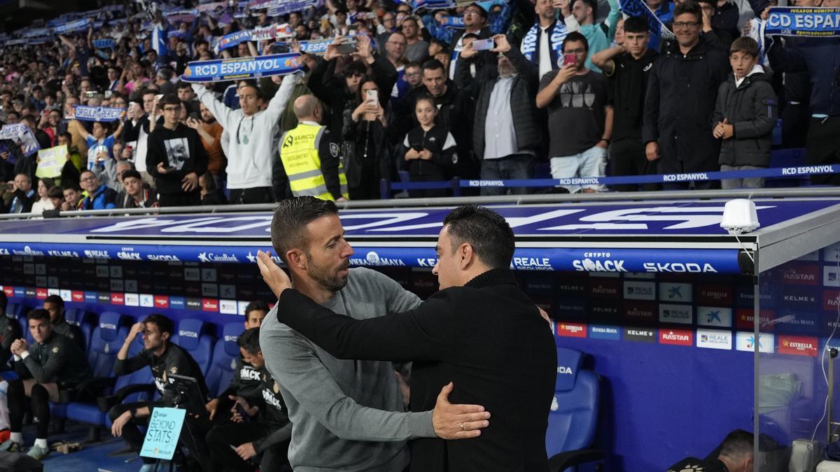 El técnico del FC Barcelona Xavi Hernández saluda a su homólogo en el RCD Espanyol, Luis García, minutos antes de comenzar el partido.