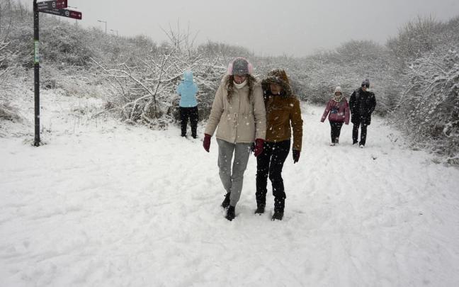 Varias personas disfrutan de la nieve en la calle de Gasteiz