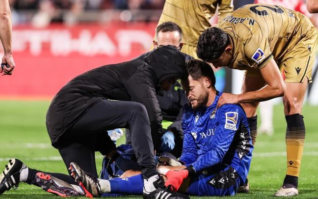 Remiro, siendo atendido por el doctor Javier Barrera y por Imanol Soroa sobre el césped de Montilivi. / AFP7 VÍA EUROPA PRESS