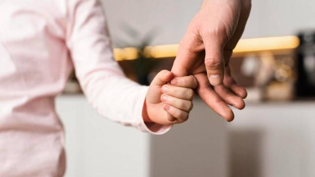Un menor sostiene la mano de su progenitor
