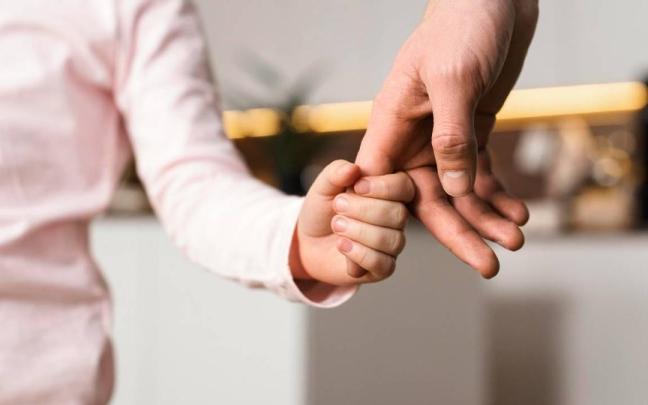 Un menor sostiene la mano de su progenitor