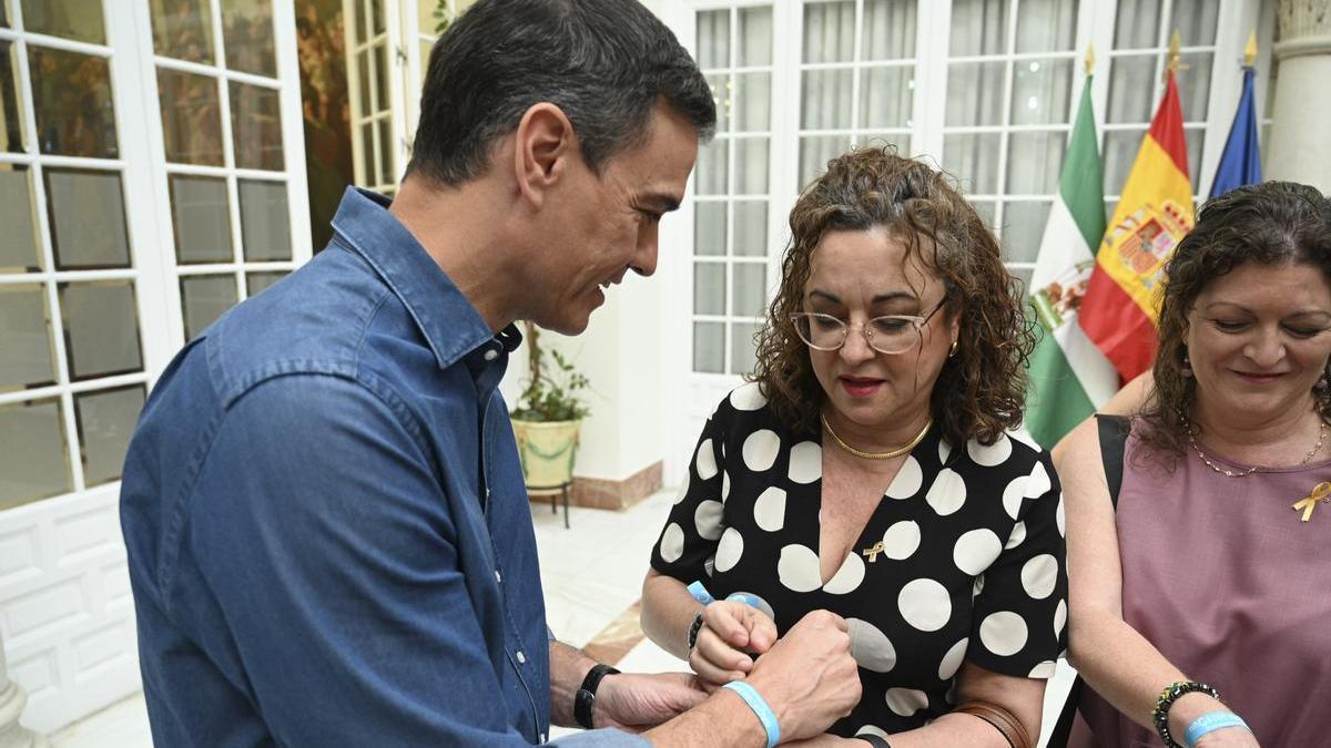 Pedro Sánchez se pone una pulsera que reivindica la lucha contra la enfermedad en la reunión que ha mantenido con representantes de las asociaciones de lucha contra e cáncer.