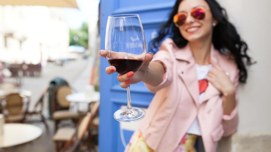 Mujer enseñándo su copa de vino.