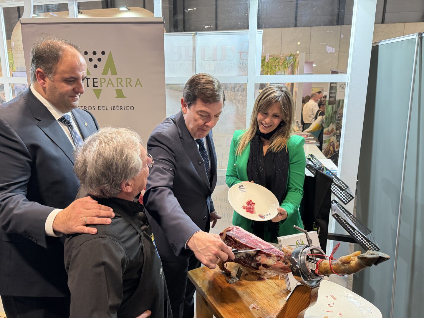 Alfonso Fernández Manueco, presidente de Castilla y León, junto a Roberto José Martín Benito, alcalde de Guijuelo, en el stand de Guijuelo en FITUR.
