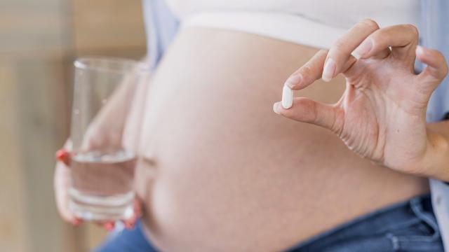 Mujer embarazada sostiene una pastilla | Freepik