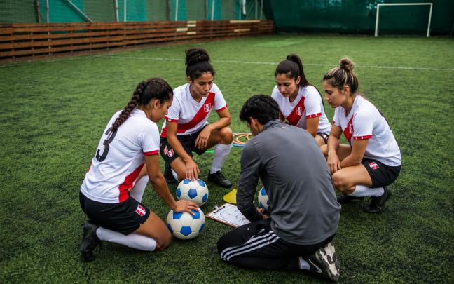 Equipo femenino de fútbol revisando indicaciones técnicas en el campo de entrenamiento