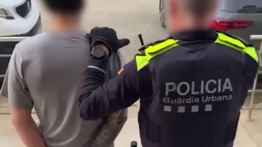Un agente de la Guardia Urbana de Barcelona custodia a uno de los detenidos.