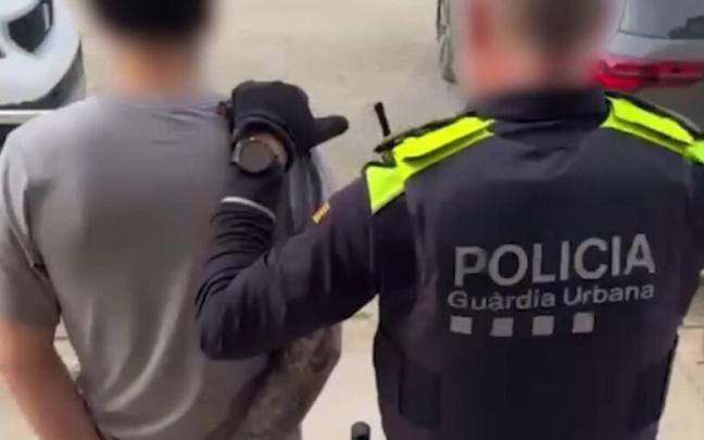 Un agente de la Guardia Urbana de Barcelona custodia a uno de los detenidos.