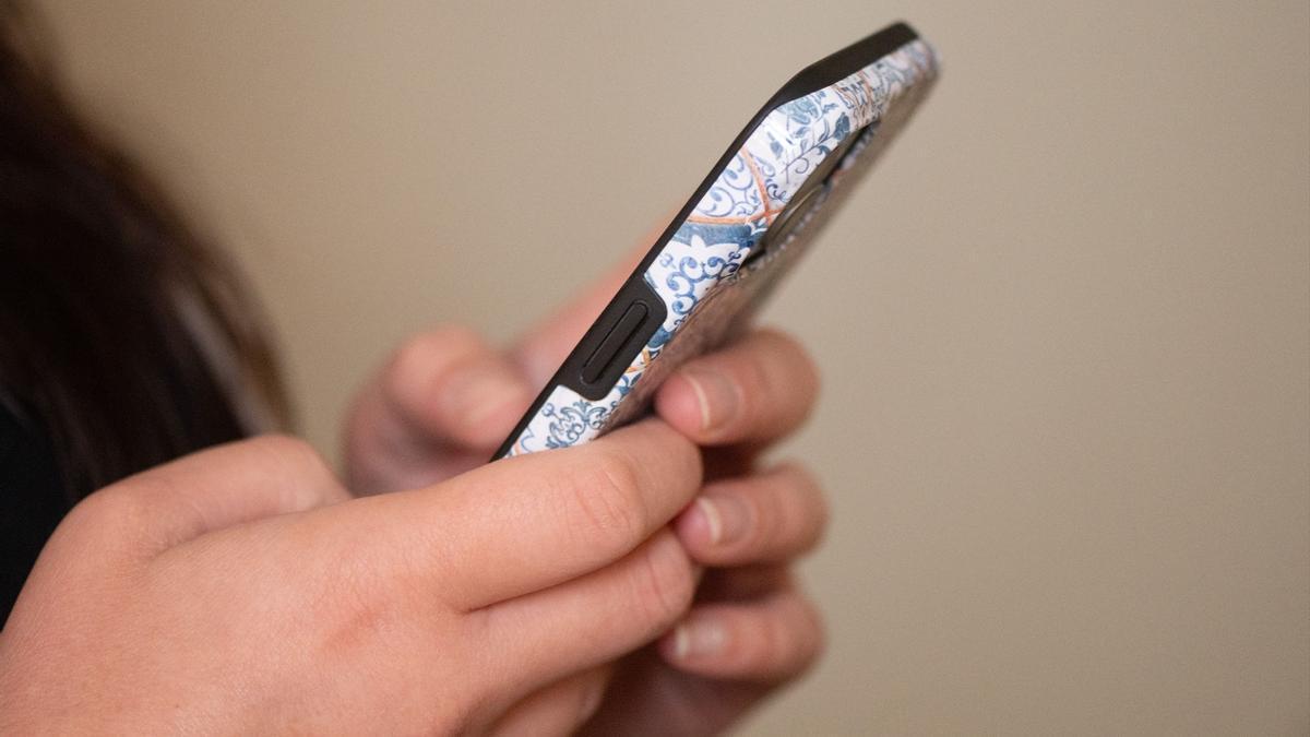 Una adolescente mira la pantalla de su teléfono móvil.