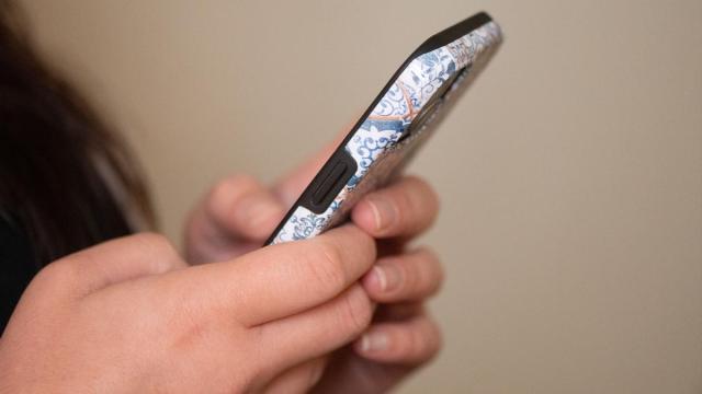 Una adolescente mira la pantalla de su teléfono móvil.