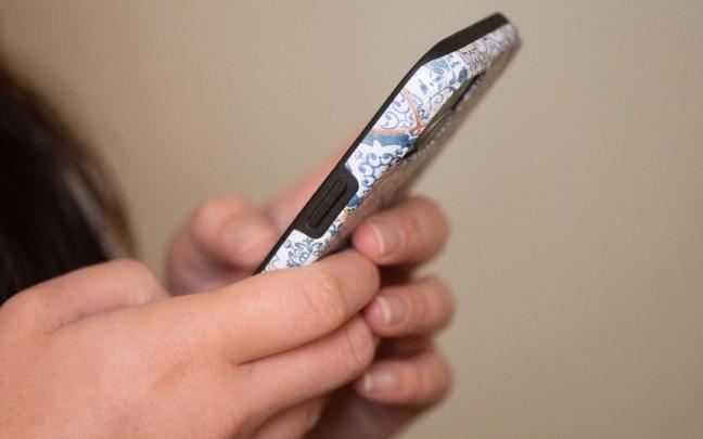 Una adolescente mira la pantalla de su teléfono móvil.