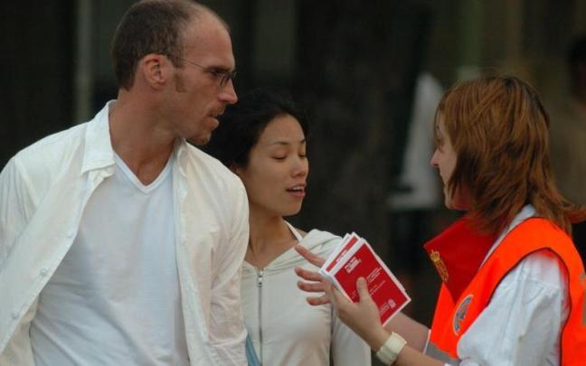 Una joven trabajadora de Protección Civil (naranjito) ofreciendo información a una pareja.