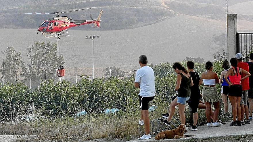 Vecinos de la calle Las Maestras observan al helicóptero cogiendo agua de las piscinas del pueblo.
