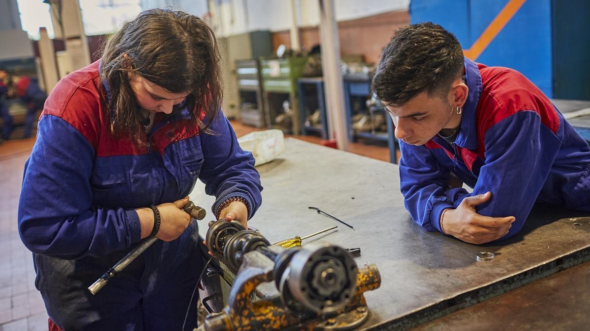 Una joven arregla un motor en un taller.