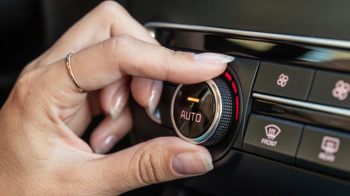 Una mujer maneja el climatizador del coche.