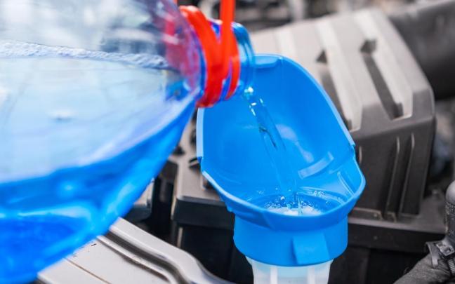 Una persona vierte líquido limpiaparabrisas.