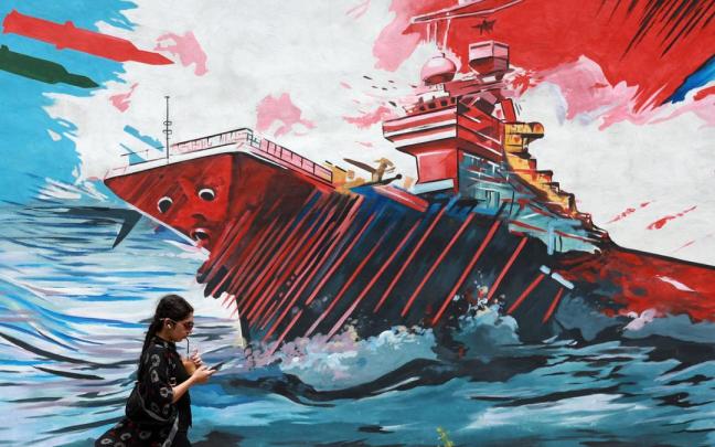 Iraníes caminan junto a un mural contra EE.UU. en Teherán.