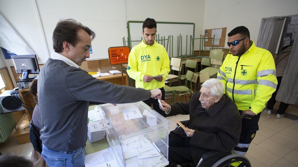 Voluntarios de la DYA acompañan a una personas con movilidad reducida a votar.