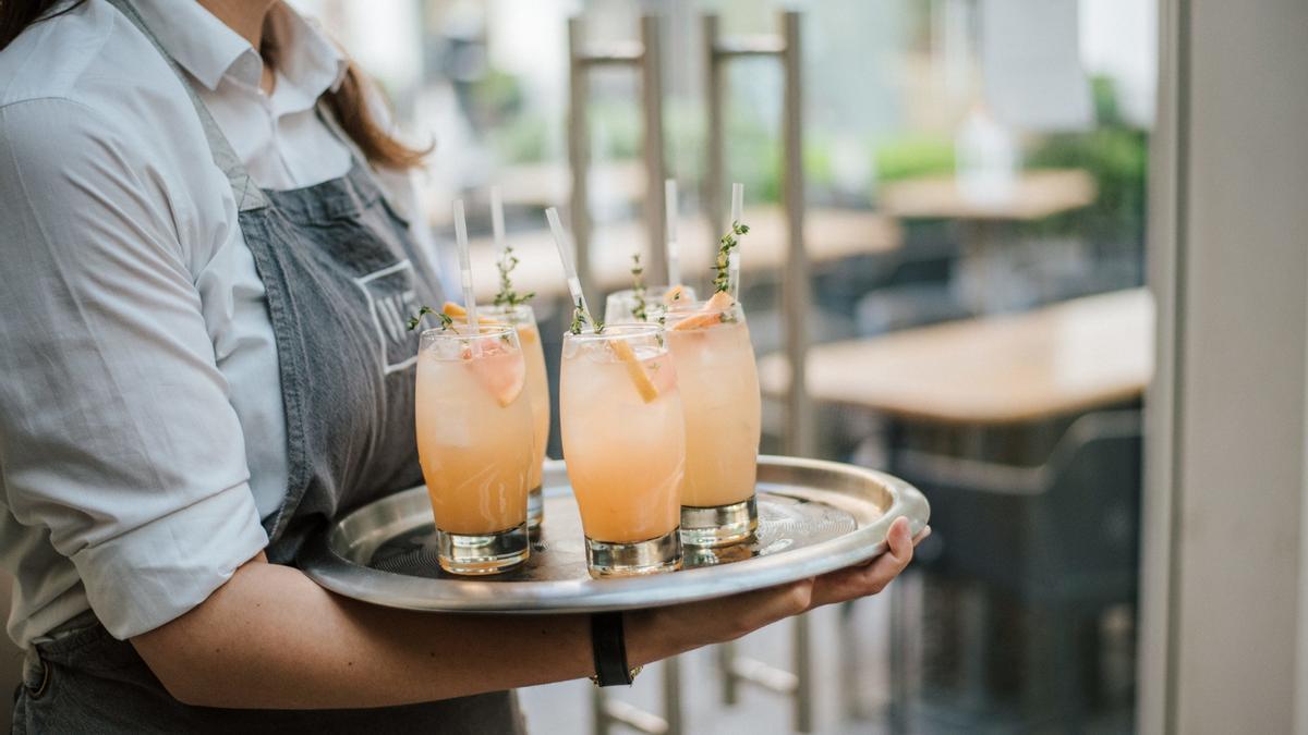 Una camarera lleva unas bebidas.