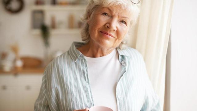 Señora mayor con una taza en la mano.