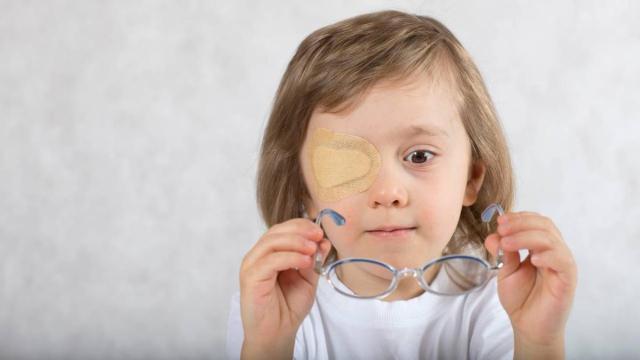 Un menor con un parche en el ojo trata de colocarse las gafas
