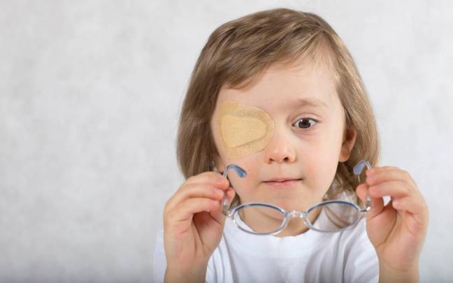 Un menor con un parche en el ojo trata de colocarse las gafas