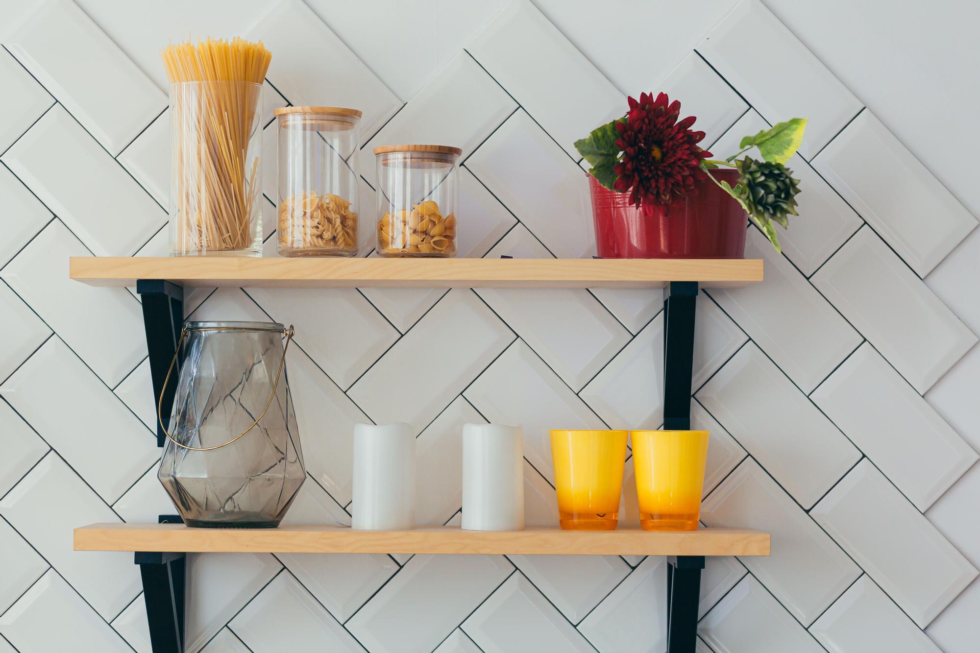 Estantería en un pequeño rincón de la cocina con plantas, elementos decorativos y tarros con algunos alimentos.