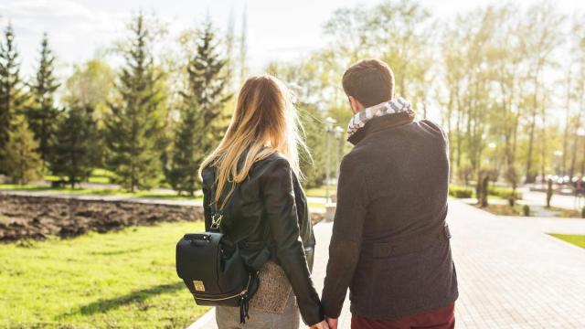 Una pareja de enamorados pasea por un parque.