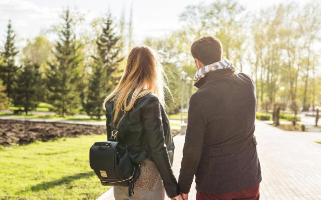 Una pareja de enamorados pasea por un parque.