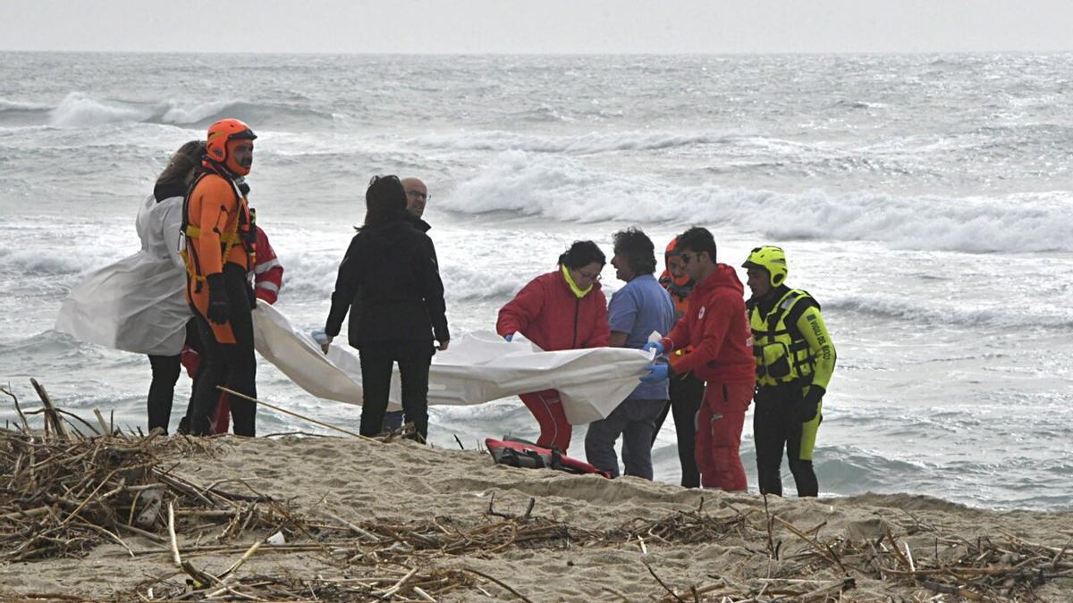 Miembros de Cruz Roja y del servicio de bomberos trasladan los cuerpos de los migrantes fallecidos cerca de las costas de Calabria.