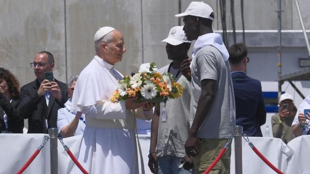 El Papa, junto a dos jóvenes migrantes, antes de arrojar un ramo de flores a las aguas del puerto canario de Arguineguín.