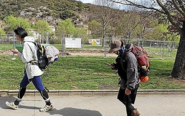 Dos peregrinas pasan por el lugar de los hallazgos de fueloil, ajenas al entorno. | FOTO: J.A.