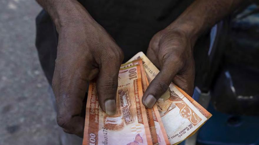 Un hombre muestra varios billetes de rupias en la India.