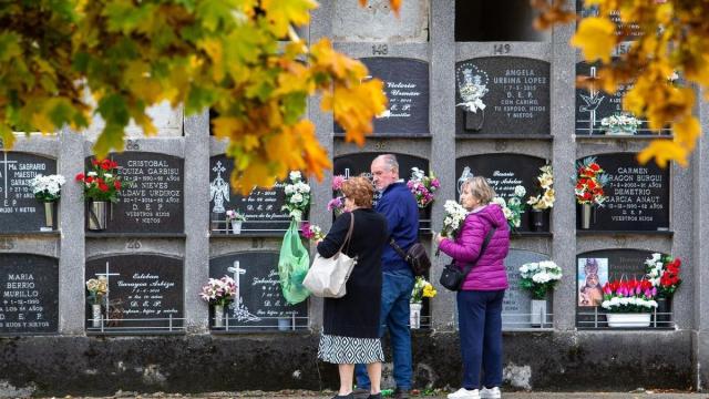 Unas personas visitan el nicho de un familiar difunto en un cementerio.