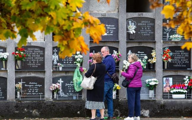 Unas personas visitan el nicho de un familiar difunto en un cementerio.