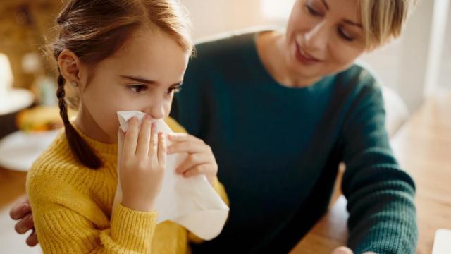 Niña con congestión nasal y un pañuelo en la mano.