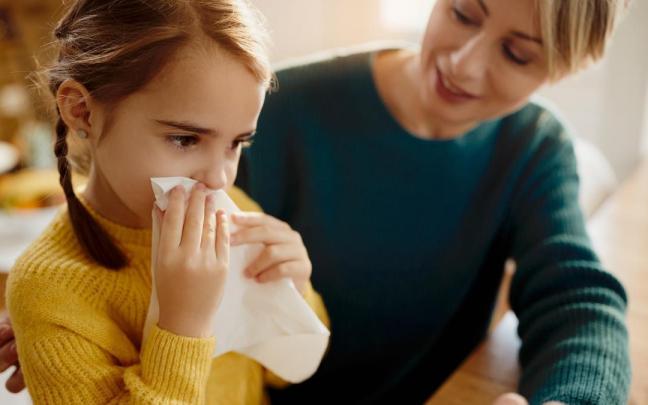 Niña con congestión nasal y un pañuelo en la mano.