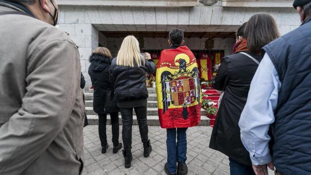 Un hombre arropado en una bandera preconstitucional acude a un homrnaje frente al panteón de la familia Franco, en el cementerio de Mingorrubio, a 20 de noviembre de 2021.