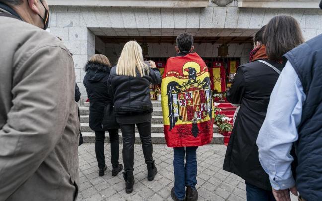 Un hombre arropado en una bandera preconstitucional acude a un homrnaje frente al panteón de la familia Franco, en el cementerio de Mingorrubio, a 20 de noviembre de 2021.