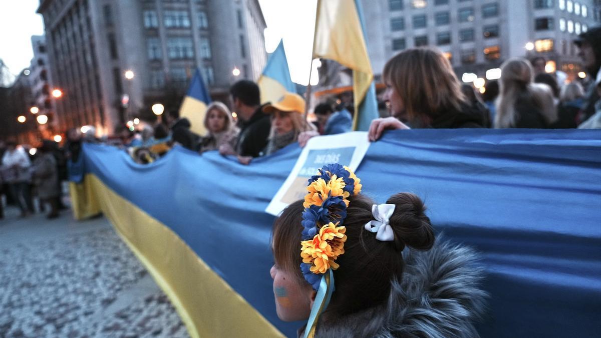 Un grupo de personas sujeta una bandera de Ucrania durante la manifestación contra la invasión rusa de Ucrania.