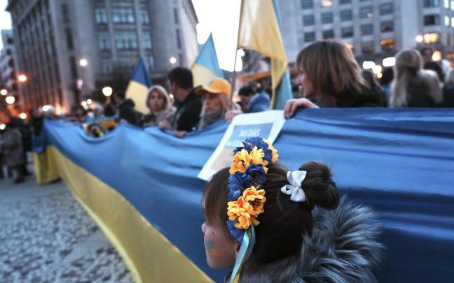 Un grupo de personas sujeta una bandera de Ucrania durante la manifestación contra la invasión rusa de Ucrania.