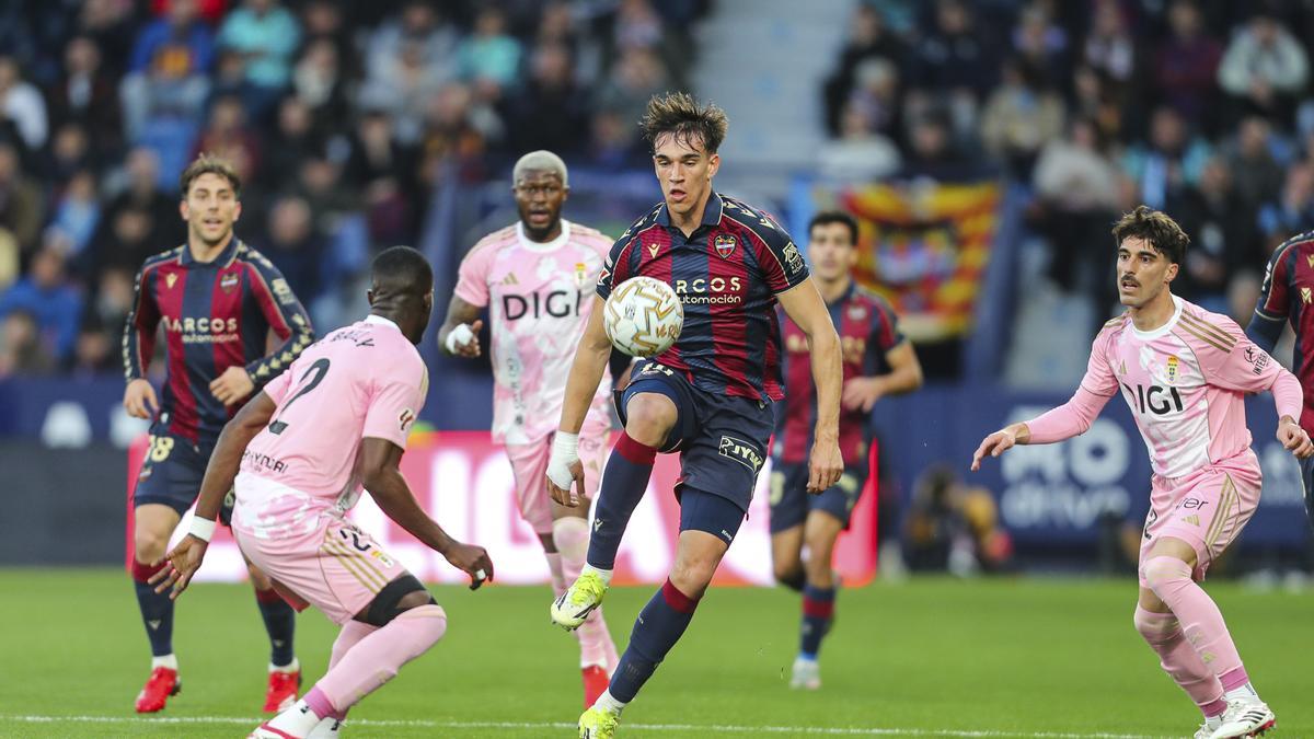 Carlos Espí, del Levante, controla el balón ante la oposición de los jugadores del Oviedo.