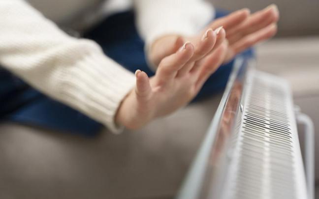 Una mujer se calienta las manos con un calentador de aire.