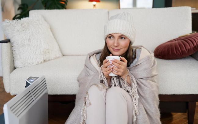 Una mujer se protege del frío en su casa