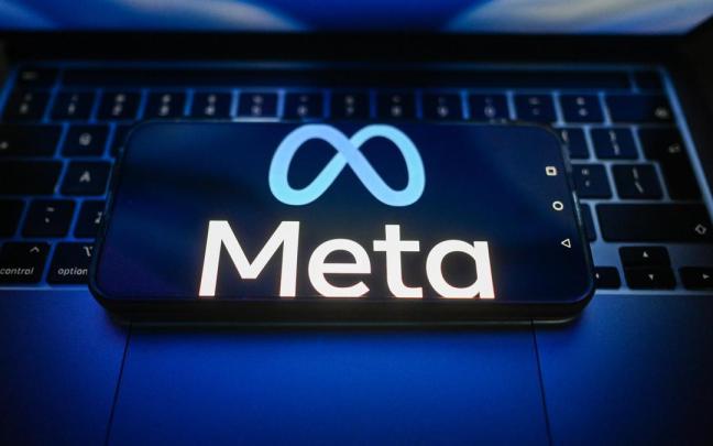 Logotipo de la empresa Meta en un teléfono móvil sobre el teclado de un ordenador portátil