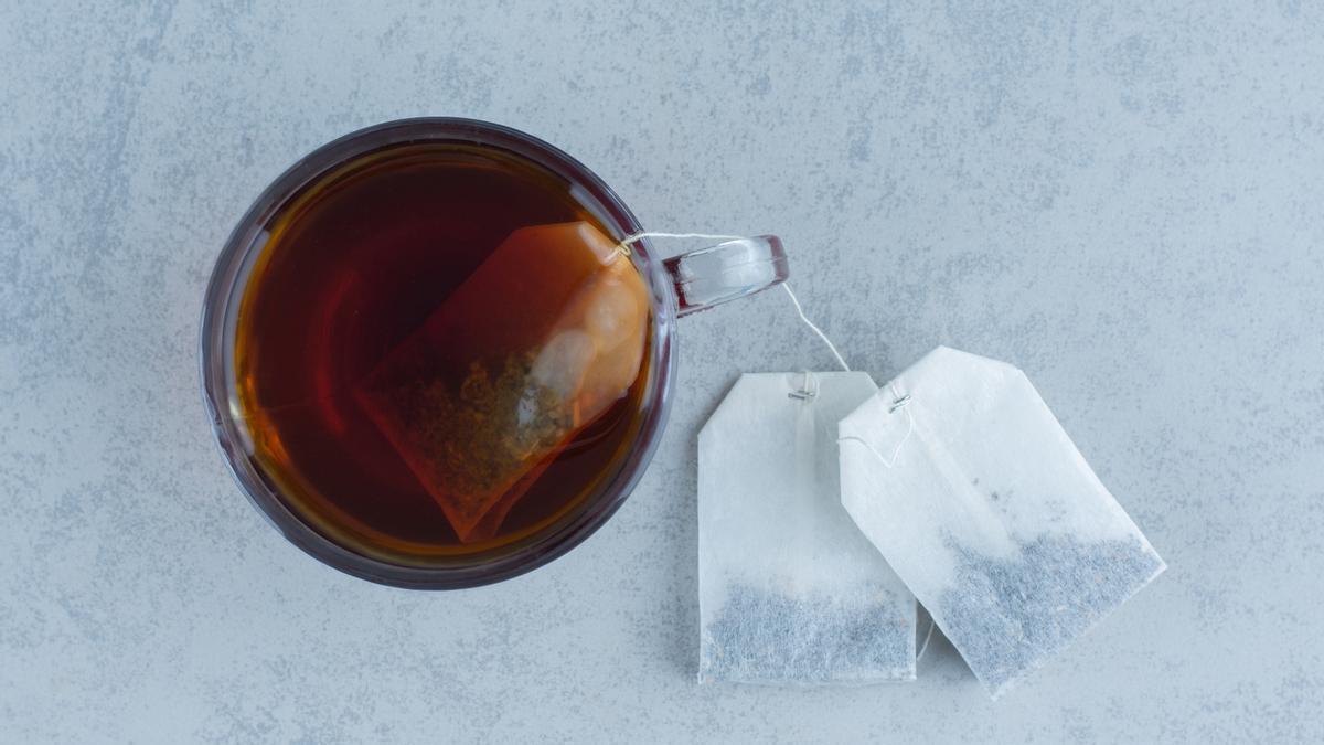 Bolsitas de té junto a un vaso con una infusión ya preparada.