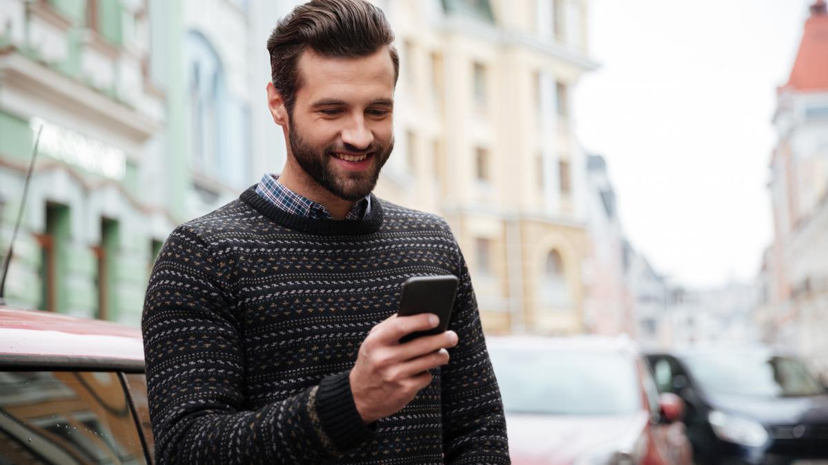 Un hombre mira su teléfono móvil en la calle.