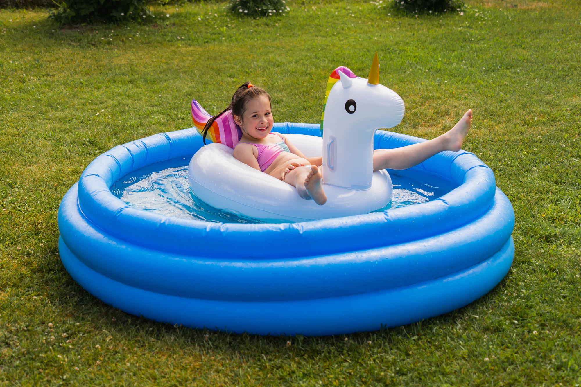 Una niña sobre un flotador en una piscina portátil.