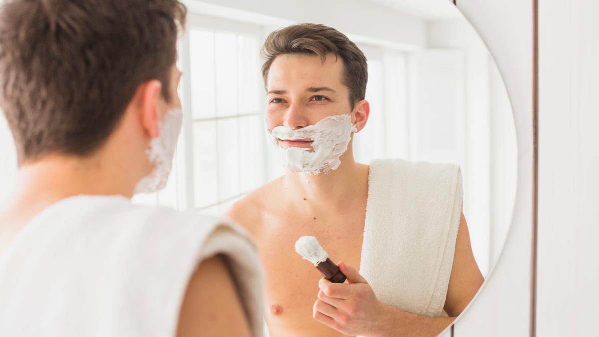 Un hombre se aplica espuma de afeitar en el rostro.