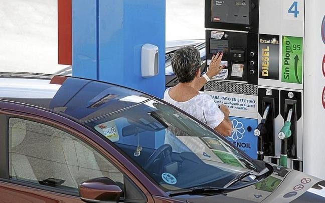 Una mujer se dispone a echar carburante a su vehículo en una estación de servicio.